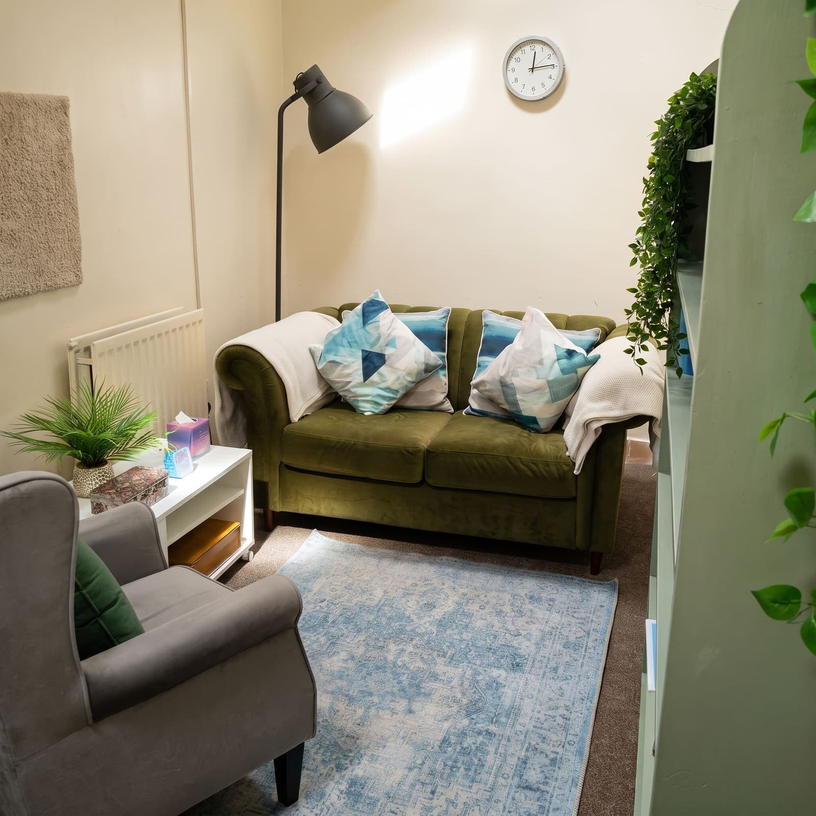 Alison's practice room at Chapter House, with a green sofa, soft cushions, warm lamplight and plants